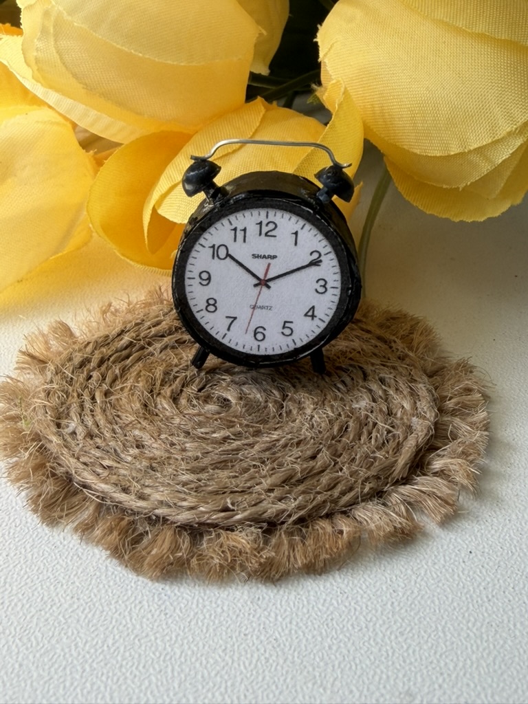 Jute rope coaster with a miniature clock, against yellow blooms